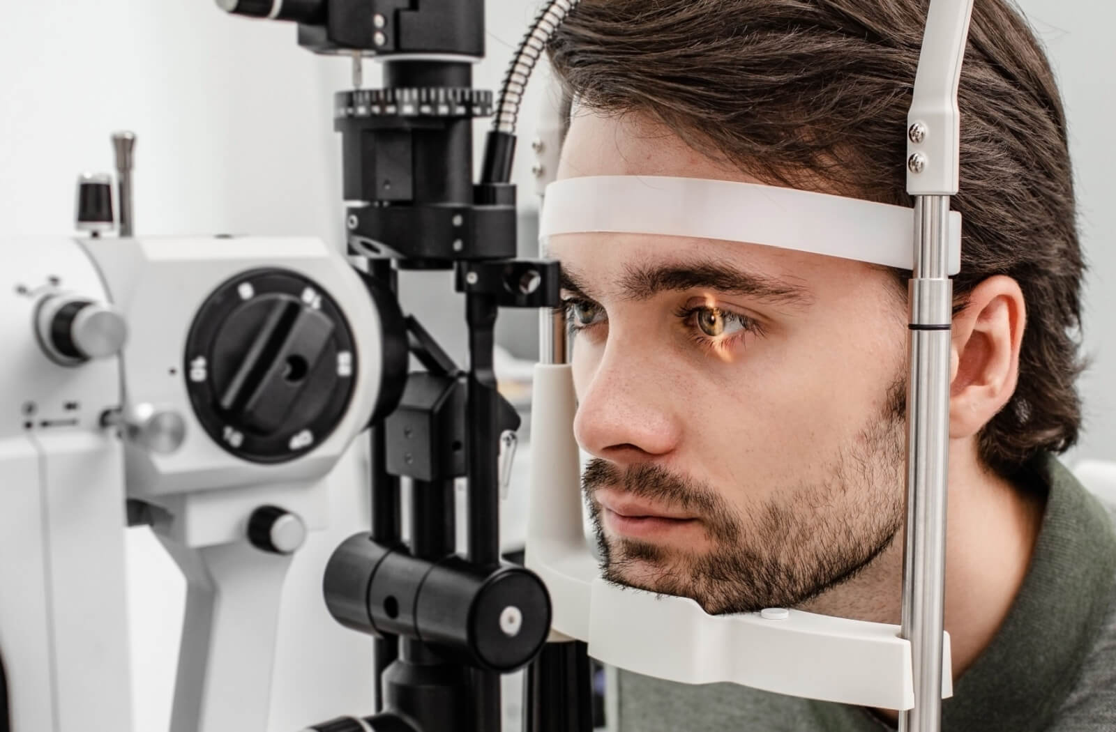 A man sitting in an optometrist's office and looking into a machine that tests his vision.