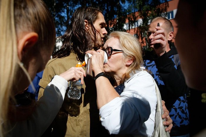 Жінка п'є воду після того, як її випустили зі слідчого ізолятора в Мінську