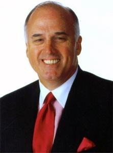 A person wearing a suit and tie smiling at the camera
Description automatically generated