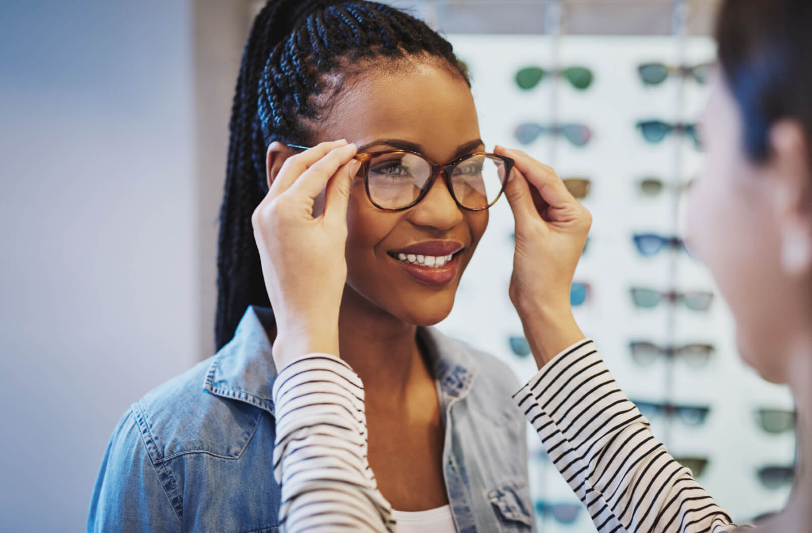 A young woman fitting prescription glasses in an optometrist's office.