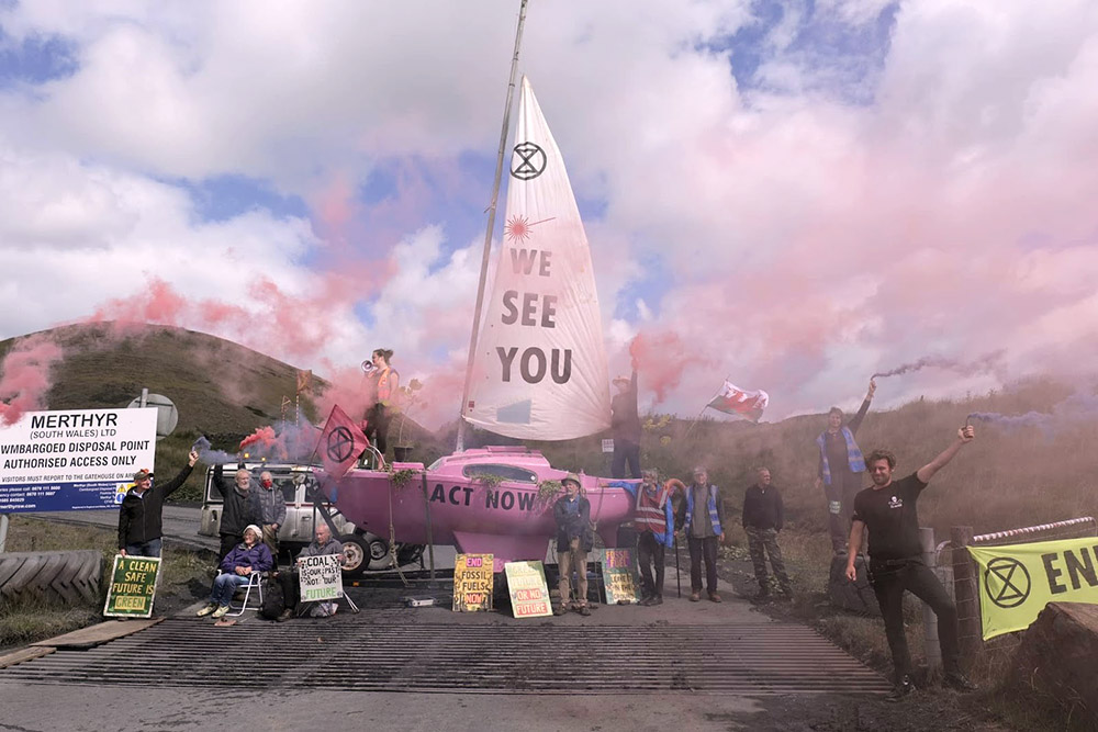 Rebels let off pink smoke as they stand by a pink boat blocking acess to the coal mine
