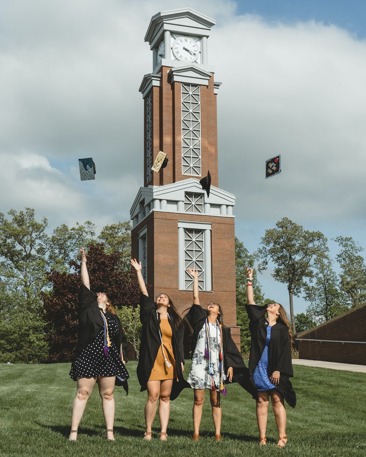 A group of four women throwing their graduation caps in the air.