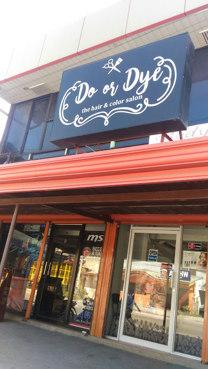 Storefront of Do or Dye hair salon with a large sign above glass doors and windows, featuring a dark orange awning.