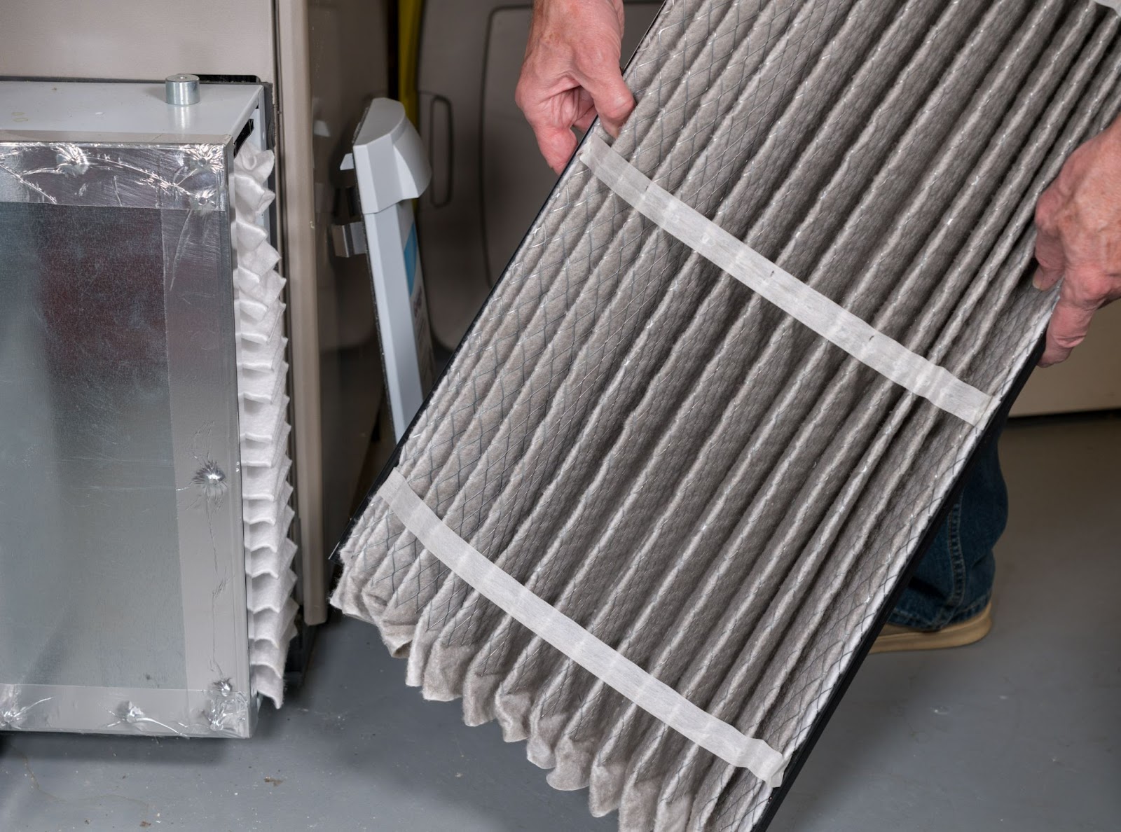 Homeowner holding dirty air filter that was just removed from air handler for a replacement.