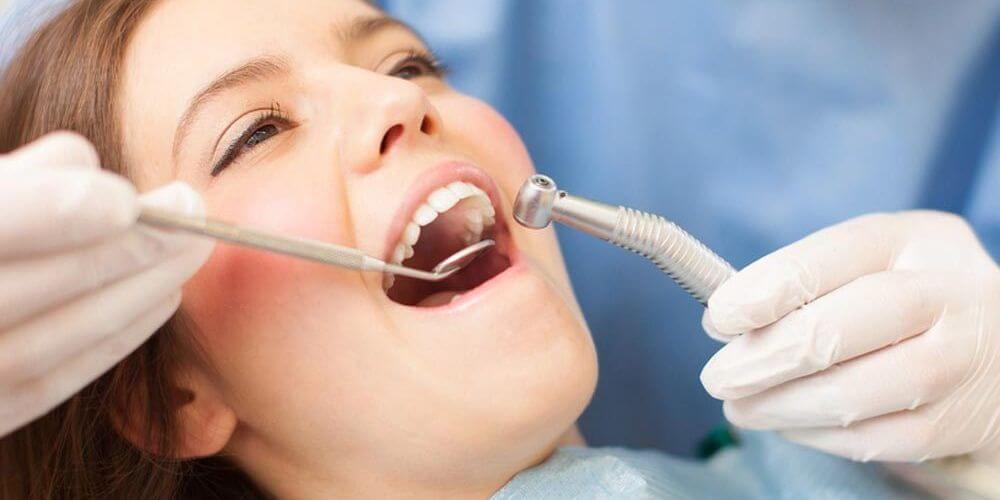 Dentiste examinant les dents d'une patiente avec un outil dentaire