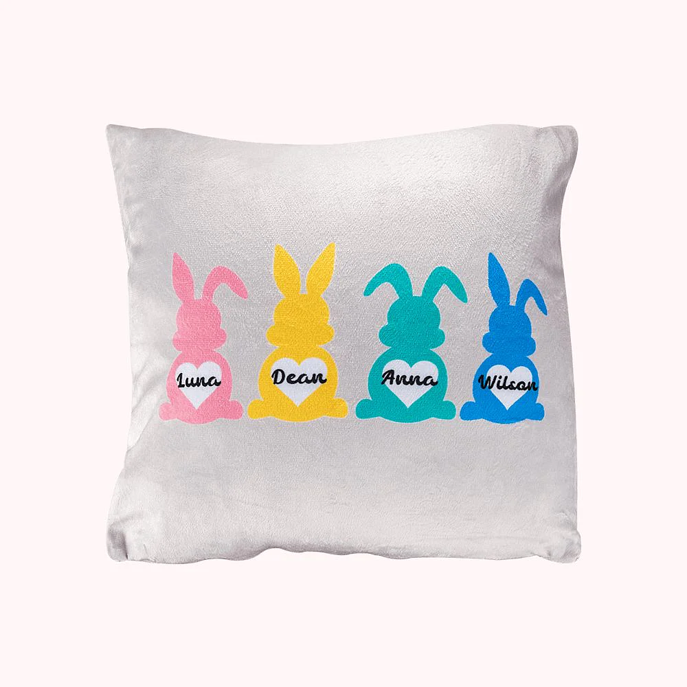 housse de coussin grise décorée par 4 lapins de Pâques de différentes couleurs et personnalisés d’un prénom. 