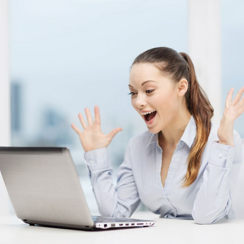 A woman with a happy face in front of a computer