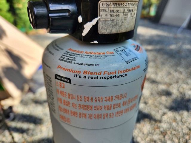 An isobutane gas canister with the displaying the phrase, "It's a real experience'