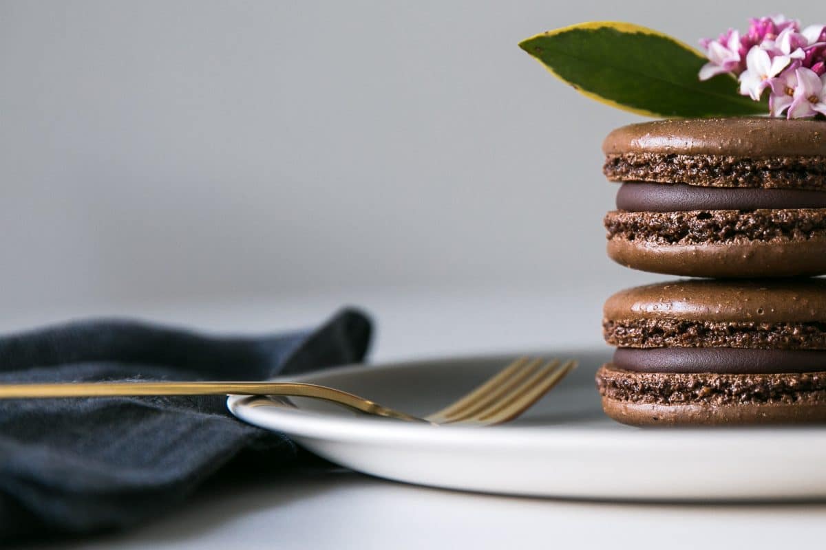 Two chocolate macarons stacked on a plate in a still life photography shoot.