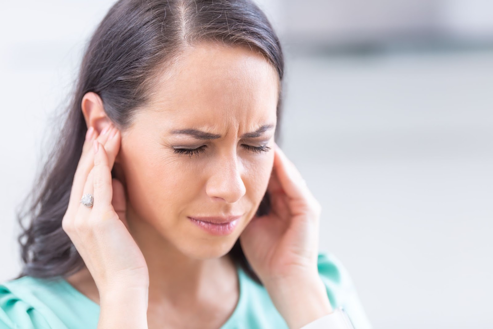 caucasian woman pressing her ears because of ringing in the ears