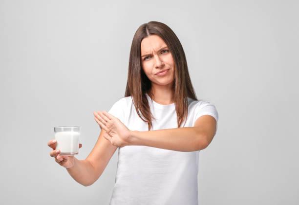 Young woman with milk on grey background. Lactose intolerance, health care concept. Young woman with milk on grey background. Lactose intolerance, health care concept. lactose intolerence stock pictures, royalty-free photos & images