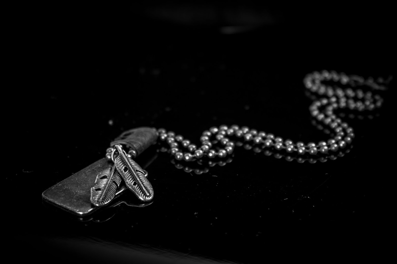 Most popular beauty and jewelry keywords on Etsy - Close up of a silver necklace with a feather charm.