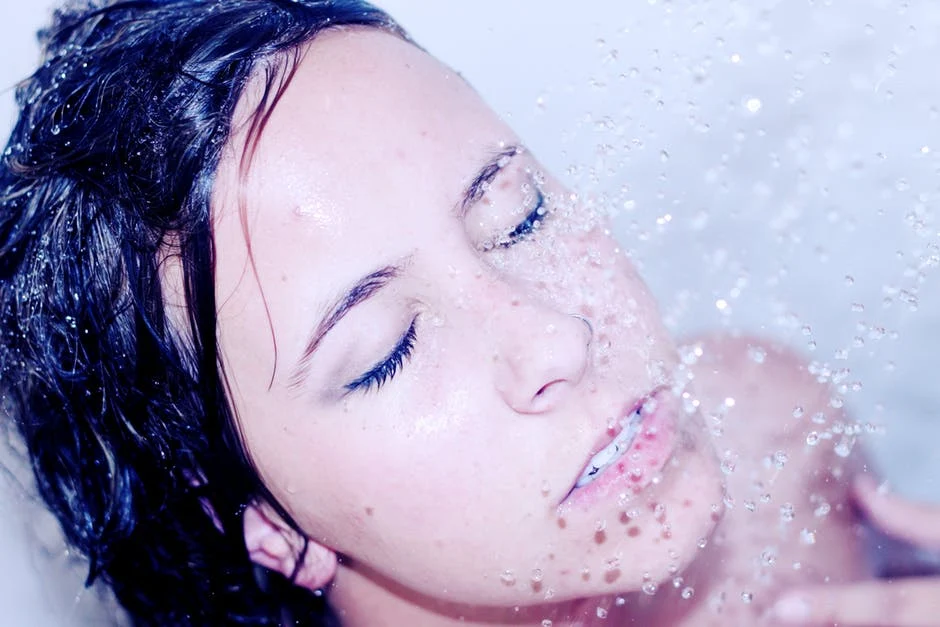 woman showering with water on face 