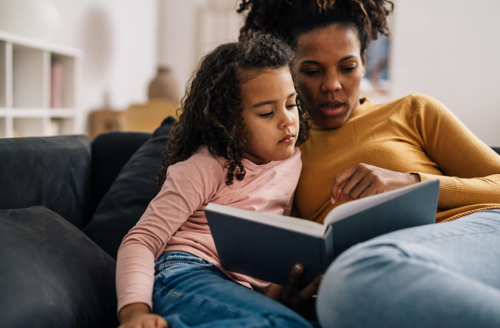 A mother reading a book to her daughter to help her develop a healthy vision.