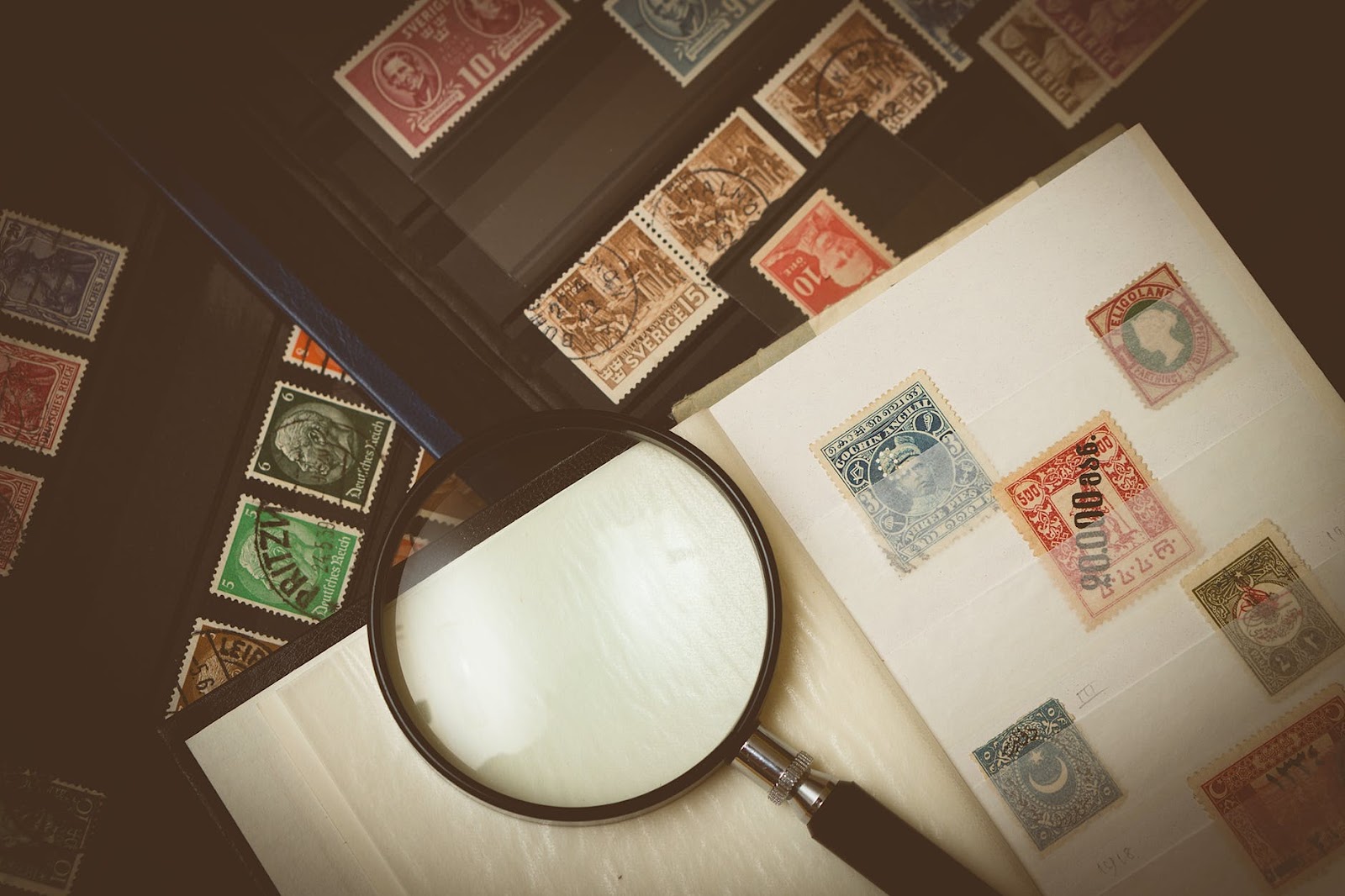 A stamp collection and magnifying glass on a table
