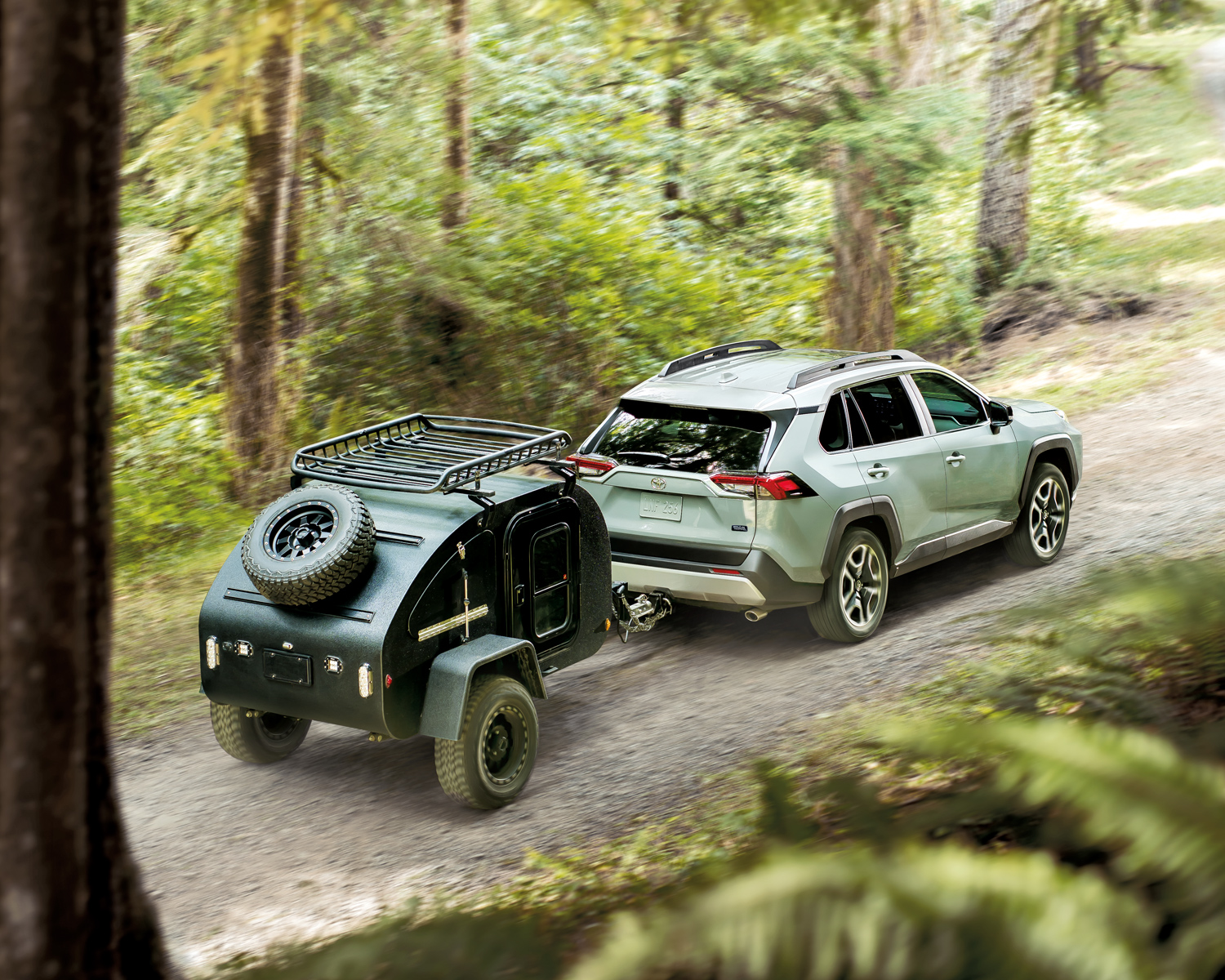 a silver RAV4 tows trailer through forest