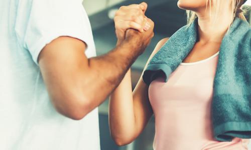 A handshake between two people illustrating that an accountability partner or personal trainer helps make exercise a habit