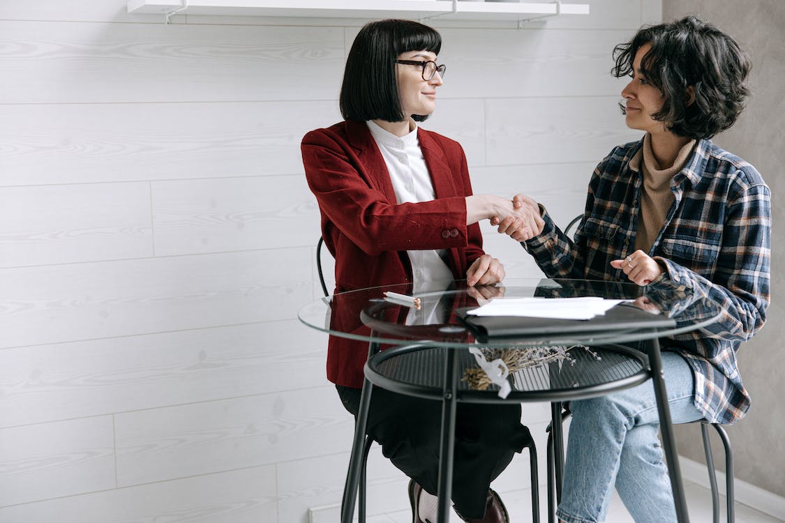 Free Woman in Red Blazer Shaking Hands with Woman in Grunge Wear Stock Photo