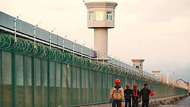 Workers walk by the perimeter fence of what is officially known as a vocational skills education centre in Dabancheng in Xinjiang Uighur Autonomous Region, China September 4, 2018.