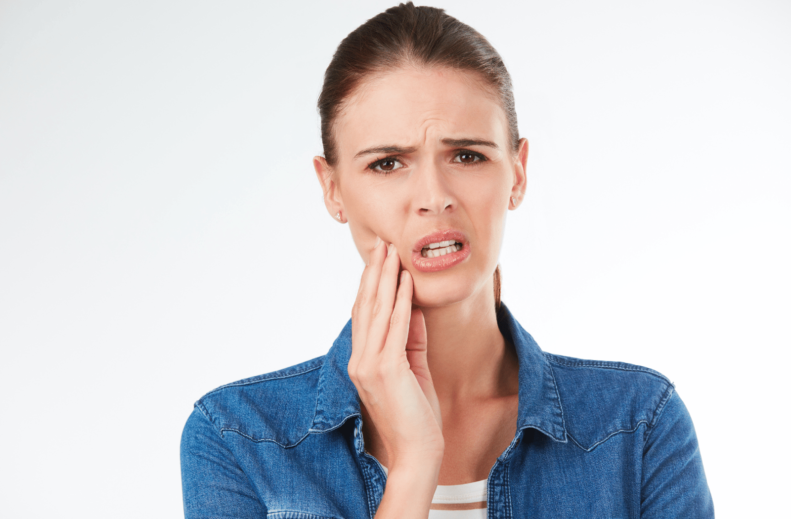 A woman with her hand on the side of her face, pressing near her jaw due to tooth pain