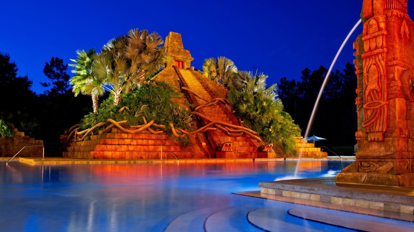 A mayan temple with lots of greenery is a center point in a large pool at a Walt Disney World Resort.