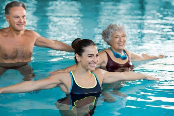 Two seniors in a swimming pool taking a swim class led by a swim instructor