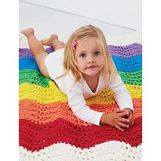 little girl lying on a super bulky crochet baby blanket