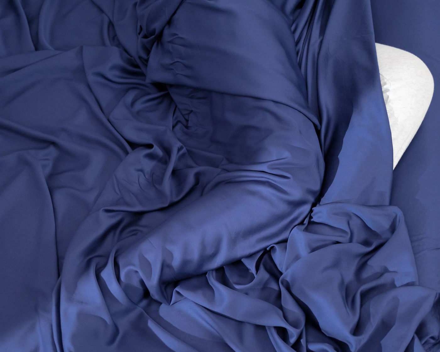 Person lying under navy blue Hush Iced sheets