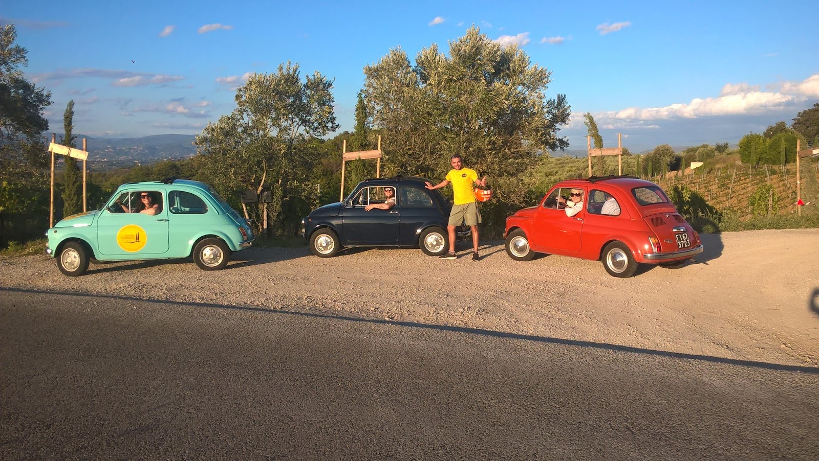 A picture of a man posing with three Vintage Fiat cars