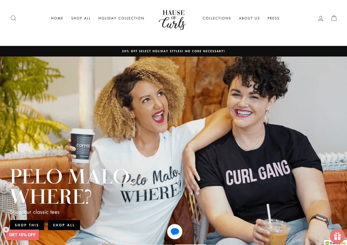 Support Black-owned businesses–A screenshot from Hause of Curls’ homepage showing two women of color smiling and wearing the brand’s shirts. One shirt is white and says, ‘Pelo Malo, Where?’, which means ‘Bad Hair, Where?’ in black letters. The other woman is wearing a black t-shirt that says ‘Curl Gang’ in pink block letters.  
