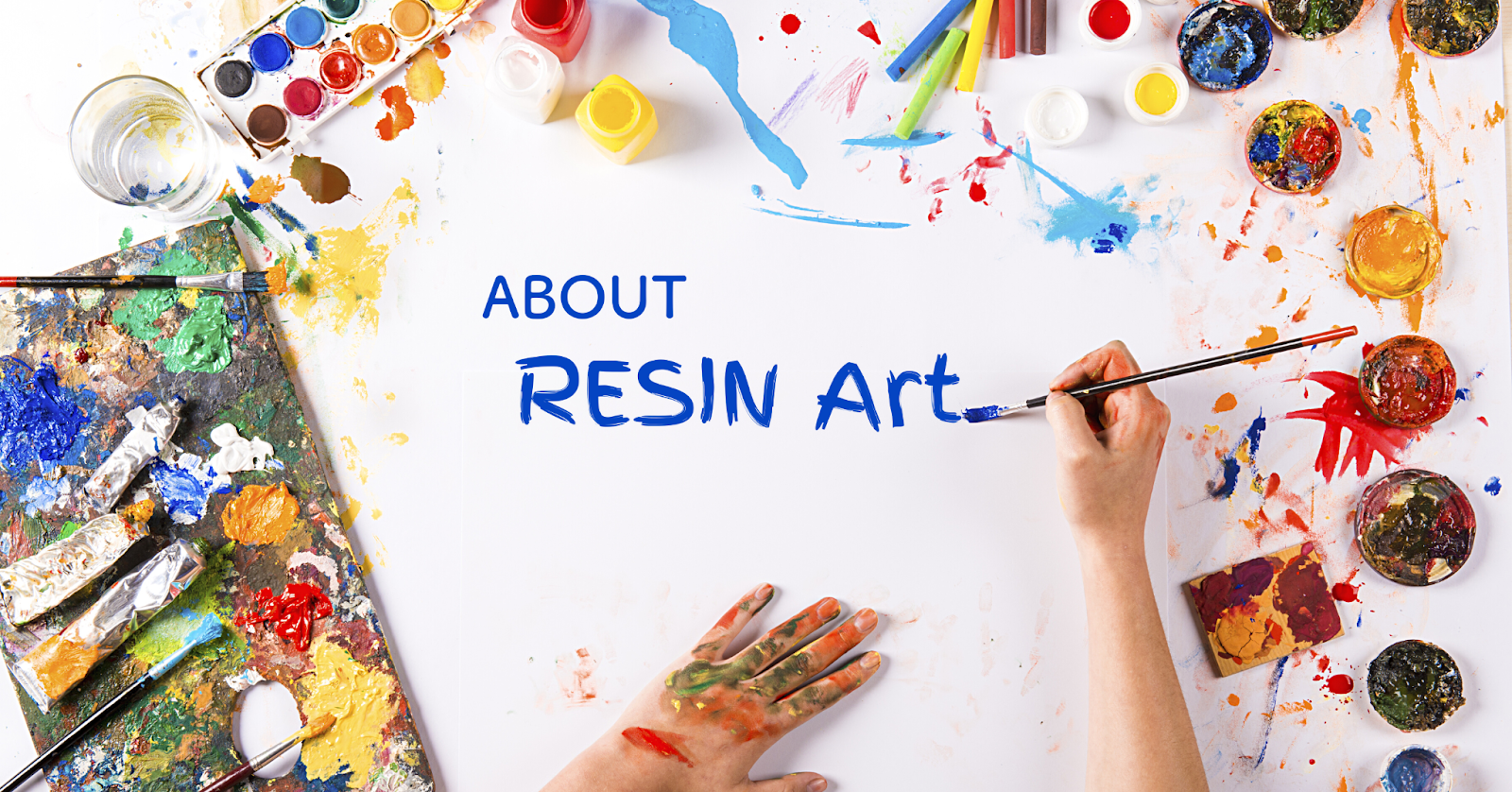 カラフルな画材に囲まれた中心のスペースに青文字でABOUT RESIN Artと筆で描いている様子