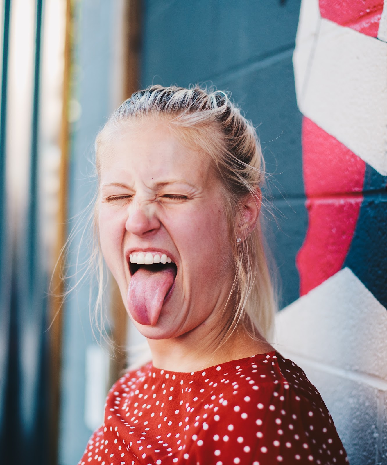 A young lady with her mouth open wide and her tongue sticking out.