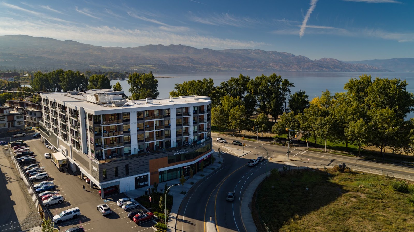 the shore kelowna apartment hotel from the side-back view, looking out over the lake, Gyro beach and Okanagan Valley mountains in the distance