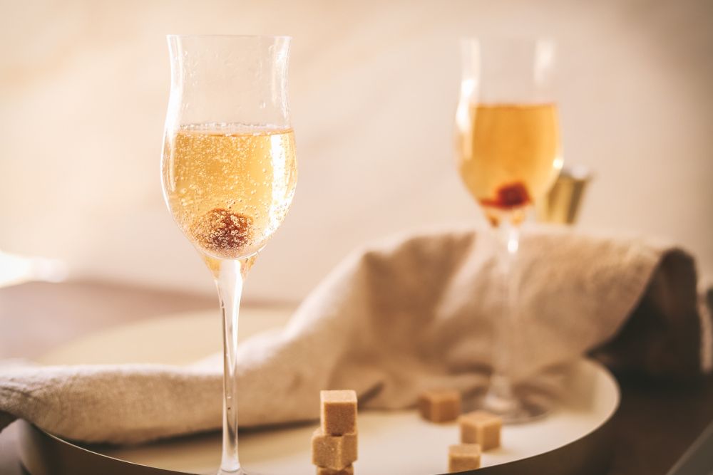 Two glasses of champagne cocktails, with a sugar cube dissolving in the bottom. 