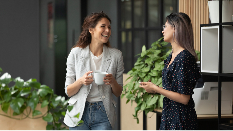 Two women laughing together during a coffee break