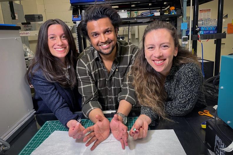 Laura Rupprecht, Atharva Sahasrabudhe, and Sirma Orguc hold parts of their invention in a lab