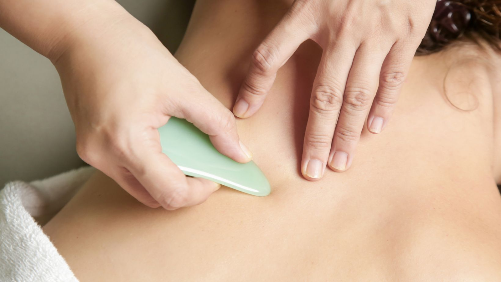 A person receiving a gua sha treatment on their trapezius muscle