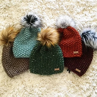 5 textured knit hats with pom poms on fur background