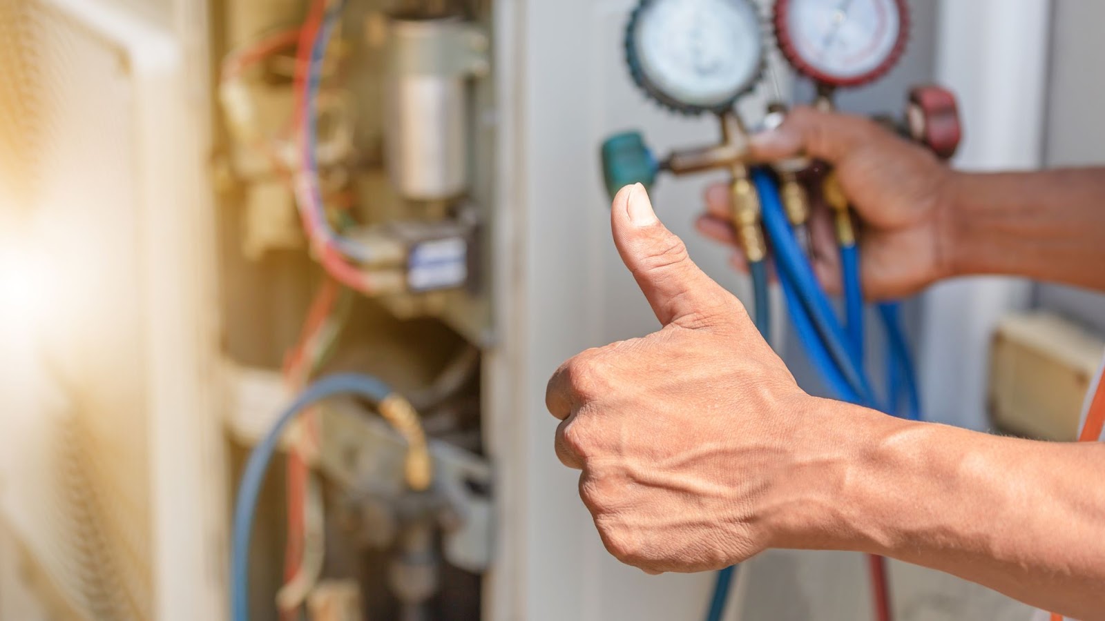 An expert making adjustments to an HVAC system while showing a thumbs up. 