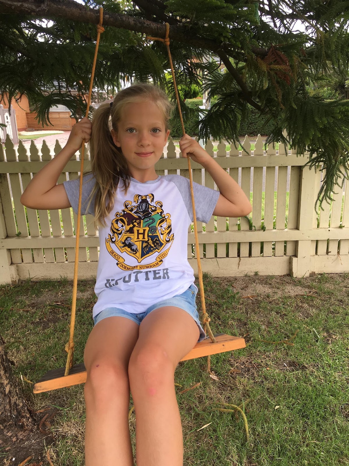 Girl wearing Harry Potter tshirt while sitting on a swing.