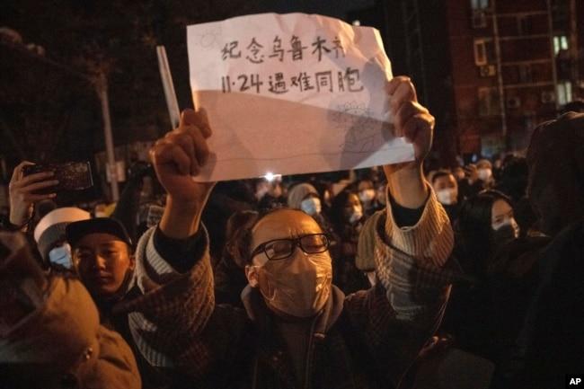 北京市民手举纪念乌鲁木齐11.24死难者的标语参加示威活动。（2022年11月27日）
