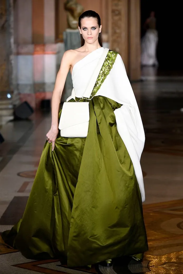 Model struts the runway in a beautiful white and green dress for the fashion show