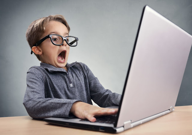 A child looks shocked while problem-solving code on his computer screen