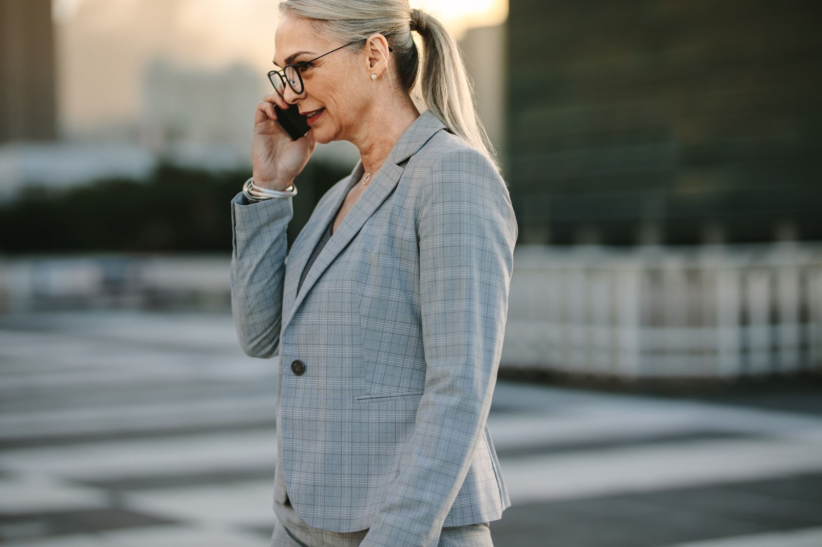 Foto de uma mulher de meia idade, vestida com roupas formais de trabalho, falando em seu celular, ilustrando a resolução de problemas por meio do teletrabalho e do remote everything