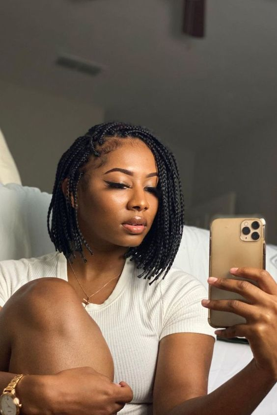 a lady rocking bob short braids and holding her cellphone