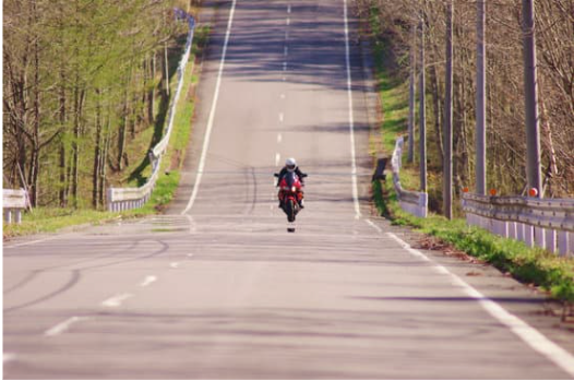 front view of a motorcycle on a road near trees