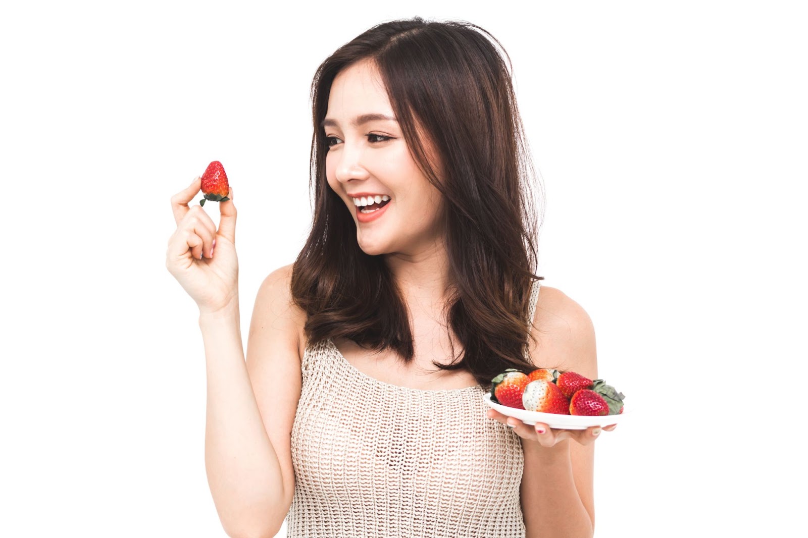Woman eating fresh strawberry on white background.