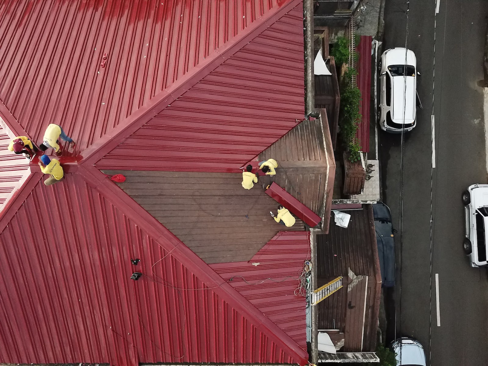 Several people repairing a red metal roof