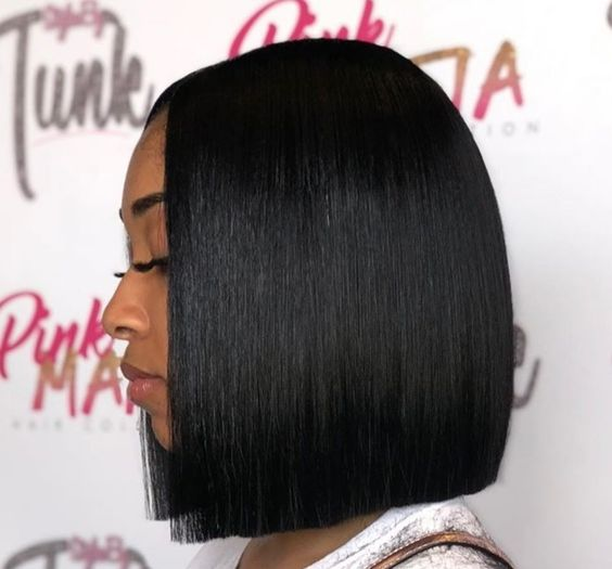 a black lady posing side view, rocking a blunt-cut bob wig