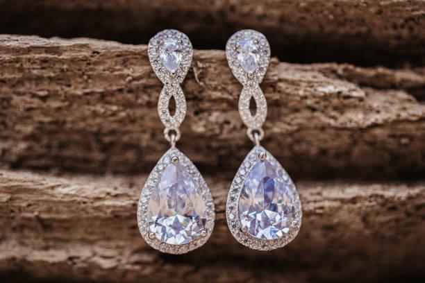 diamond wedding earrings hanging on wooden background diamond wedding earrings hanging on wooden background, selective focus diamond earings stock pictures, royalty-free photos & images